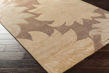 Close-up of the Defoe Area Carpet. Hand-knotted wool rug in camel, clay, and brown with a contemporary floral pattern. Corner