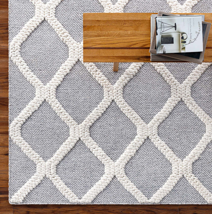 Close-up of Della Area Rug featuring a gray herringbone pattern and a white geometric design. Styleshot