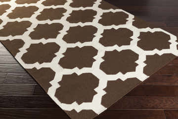 Close-up of the Depew Area Rug. The hand woven wool rug has a dark brown and ivory geometric pattern. Corner