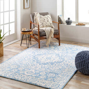Sunlit room with a Devine Hand Tufted Wool Area Rug in ice blue and ivory, leather chair, and blue pouf. Roomscene-Rectangle