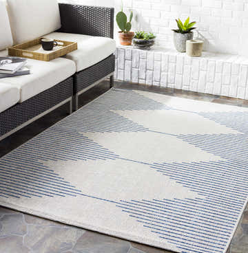 Outdoor patio scene with Stephan Blue & Cream rug, woven sofa, white cushions, and brick accent wall. Roomscene-Rectangle