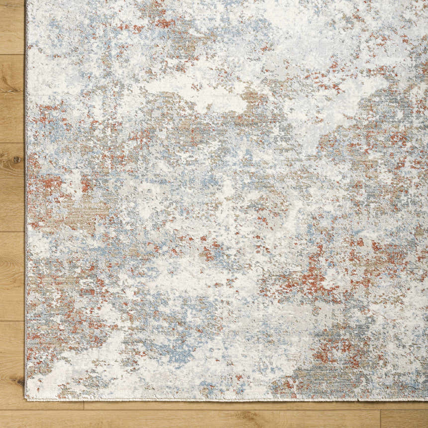 Close-up of the Dinos Thick Luxe Rug. Abstract design in light gray, blue, and nutmeg colors. Soft texture. Corner