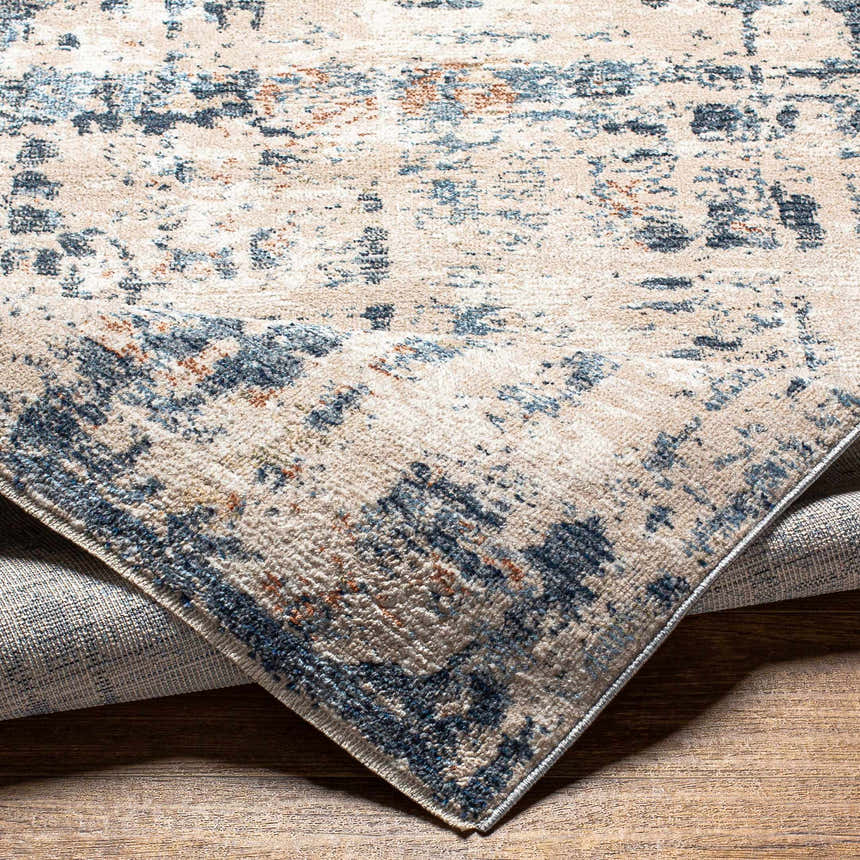 Close-up of the Dalama Area Rug, showing its contemporary dark gray, ivory, and blue abstract pattern and soft polyester texture. Fold