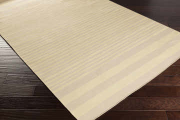 Close-up of the Donaghadee Area Carpet. Ivory and yellow striped, hand-woven cotton rug on dark wood floor. Corner