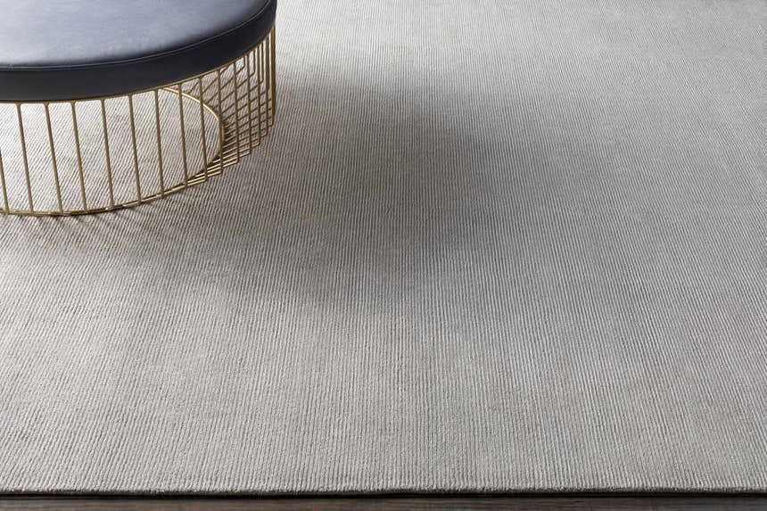 Close-up of light gray Donegal Carpet showing subtle texture and a gold accent table. Hand knotted wool and viscose rug. Styleshot