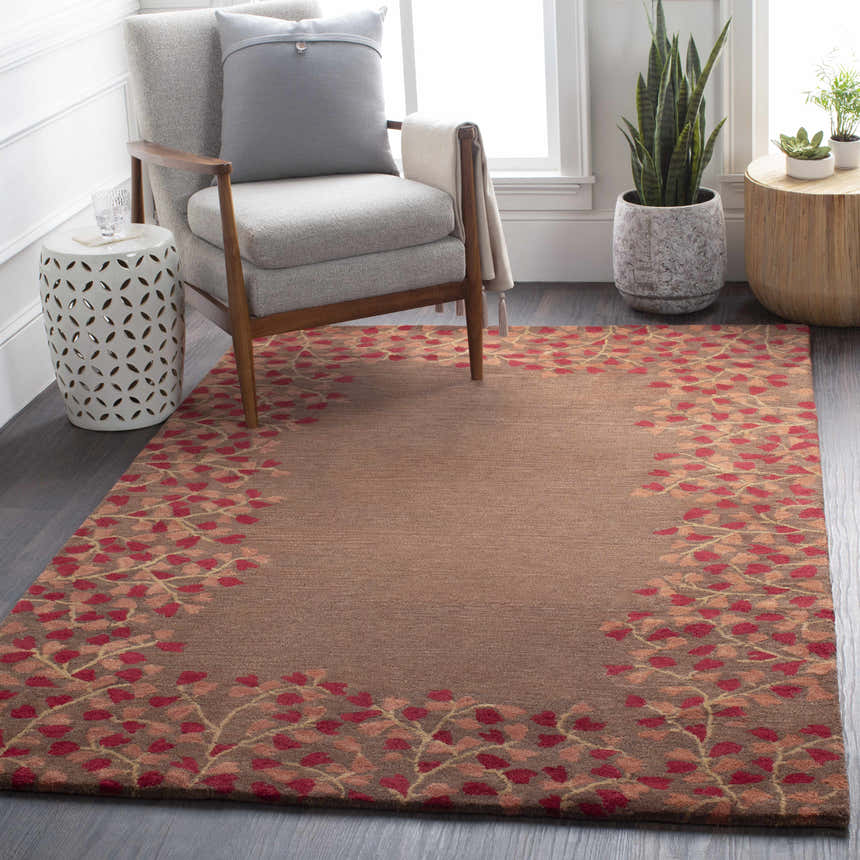 Living room scene with a brick red and brown Dovercourt Clearance Rug, gray chair, and plants. Roomscene-Rectangle