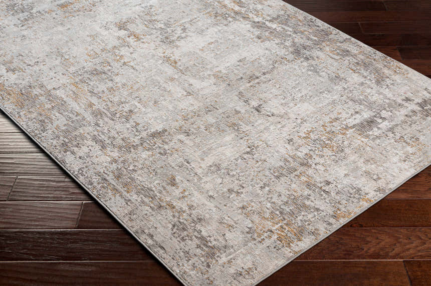 Close-up of Dowell Luxe Textured Area Rug on dark wood floor. Abstract design in gray, off-white, and mustard. Corner
