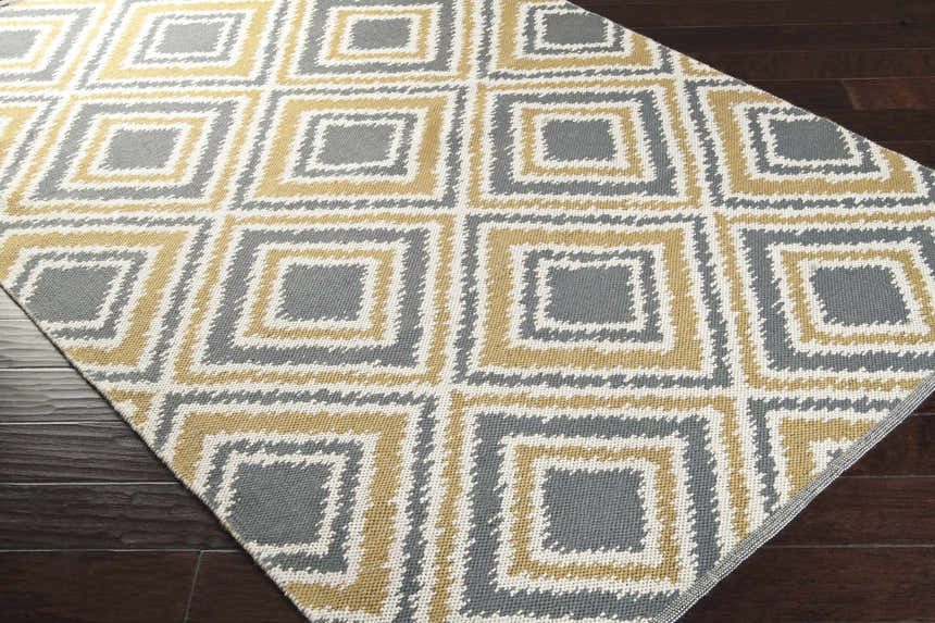 Close-up of the Druid Area Rug, a hand-woven wool rug with charcoal, ivory, and mustard diamond pattern. Corner