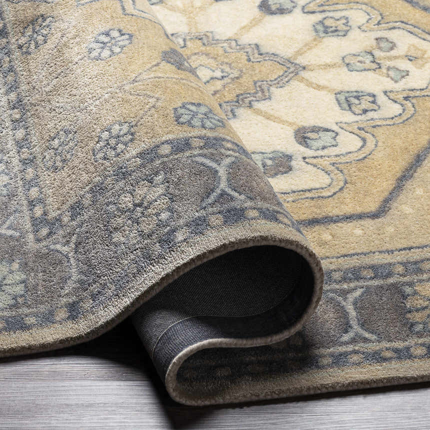 Close-up of the hand-tufted Duckenfield Area Rug. Features a traditional floral pattern in tan, beige, and gray tones. Fold