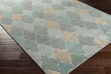 Close-up of the Eads Area Rug. Hand-knotted wool rug with beige, ice blue, light sage, and light slate quatrefoil pattern. Corner