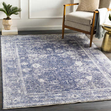 Living room scene with a denim and light beige Eastham Luxe Area Rug, wood chair, and gold side table. Roomscene-Rectangle