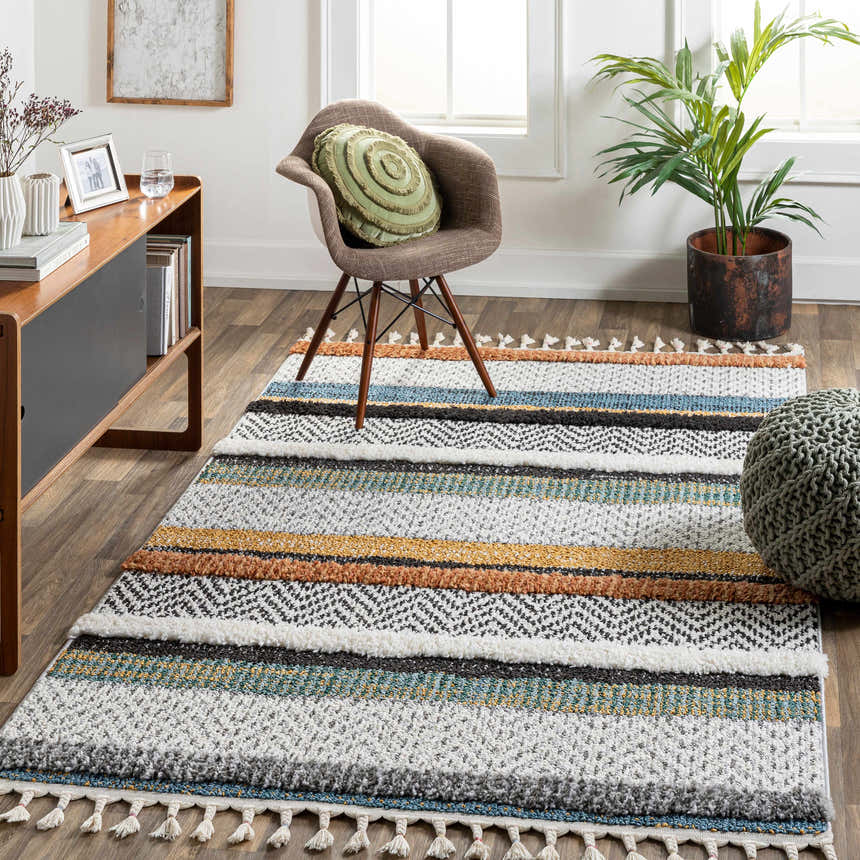 Living room scene with a striped Edmundston Area Rug in black, blue, and bone tones. The rug is styled with a chair and a green pouf. Roomscene-Rectangle