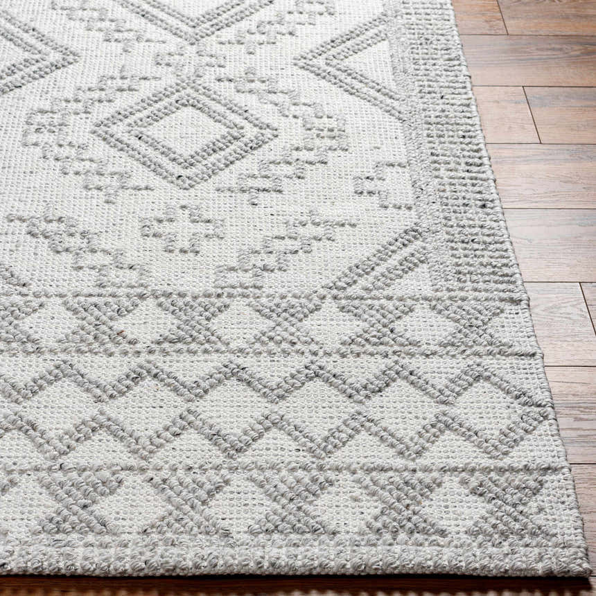 Close-up of the Elin Area Rug showing its arctic stone and dark gray geometric pattern and hand-woven texture. Front
