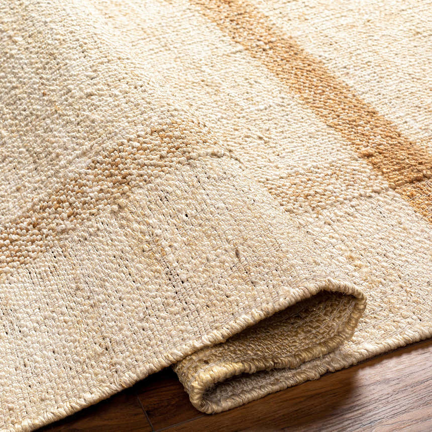 Close-up of the Errin Jute Area Rug, showing the beige and camel color, hand-woven texture, and geometric stripe detail. Fold