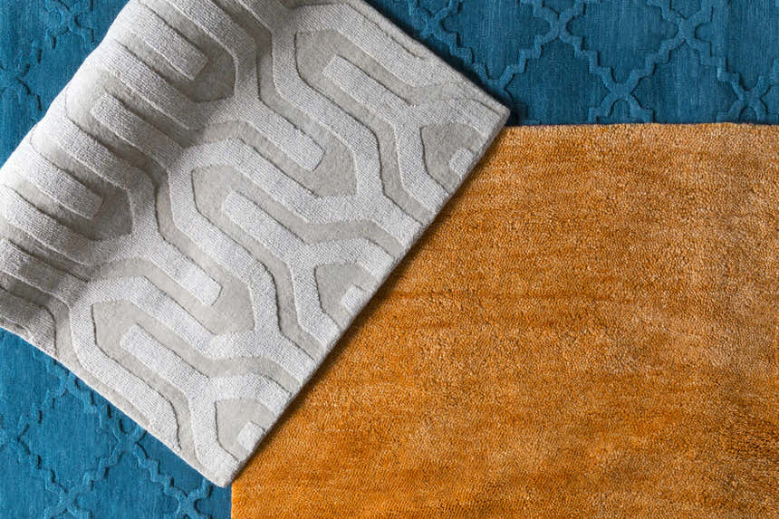 Close-up of the Plainville Area Rug. Burnt orange wool texture, geometric pattern in white and blue. Styleshot