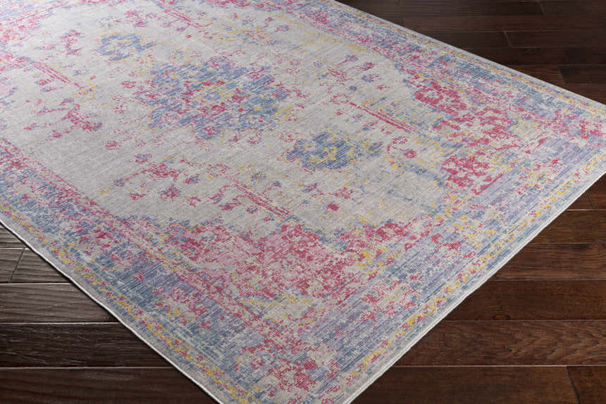 Close up of the Eufaula Area Rug. Features a traditional design with burgundy, gray, lavender, purple, red, and yellow colors. Corner
