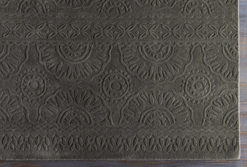 Close-up of the charcoal Eversholt Clearance Rug. Hand-loomed wool rug with a contemporary floral and geometric design. Corner