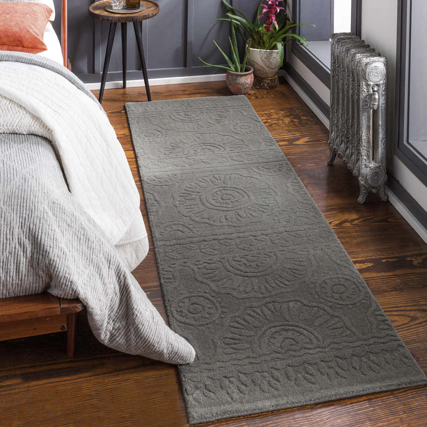 Bedroom scene with charcoal Eversholt Clearance Rug runner, wood floors, bed and vintage radiator. Roomscene-Runner