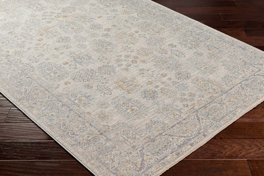 Close-up of the Coby Sage Avant Garde rug. Machine-woven polyester rug in brown, charcoal, sage, and gray on dark wood floors. Corner