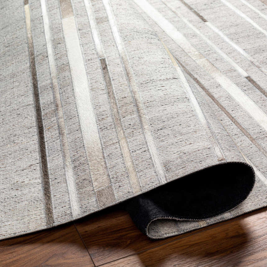 Close-up of the Fico Area Rug showing its dark brown, ivory, and tan geometric pattern and hand-crafted texture. Fold