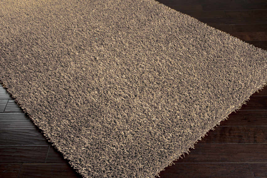 Close up of the Browder Solid Brown Shag Rug showing its texture and long pile on dark wood flooring. Corner