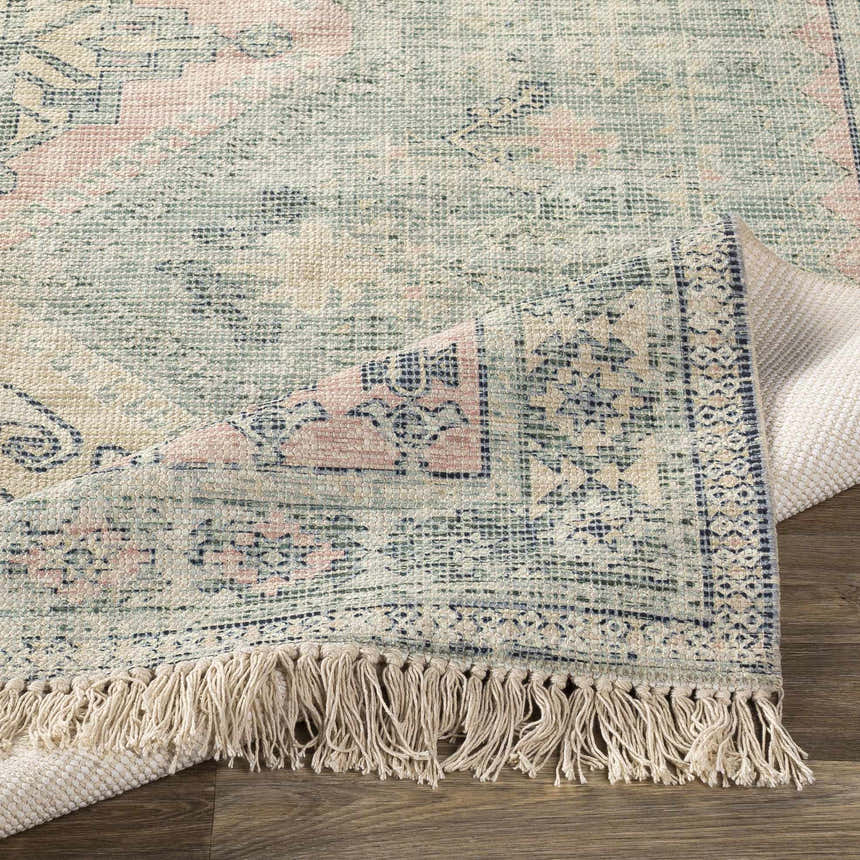 Close up of the Foraker Sage Green Cotton Rug showing its woven texture and bohemian pattern. Fold