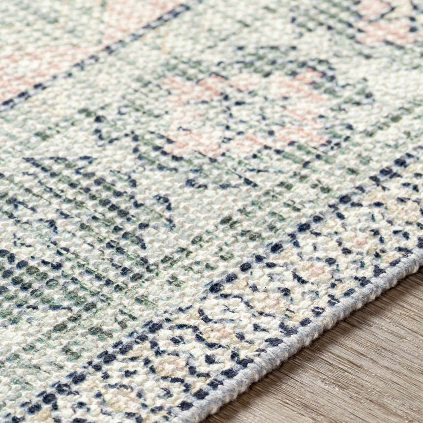 Close-up of the hand-woven Foraker Sage Green Cotton Rug, showcasing its bohemian pattern, sage, pink, and white colors. Texture
