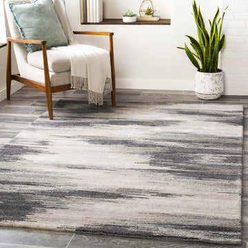 Living room scene with a gray Farnhamville Area Carpet, chair, plant, and shelf. Roomscene-Rectangle