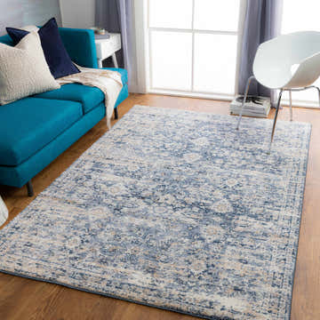 Living room with a blue sofa and the Talihina Denim Damask Area Rug in charcoal, cream, and blue tones. Roomscene-Rectangle
