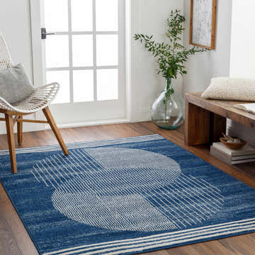 Entryway with blue Gent Area Rug featuring a geometric design, white chair, and wooden bench. Roomscene-Rectangle