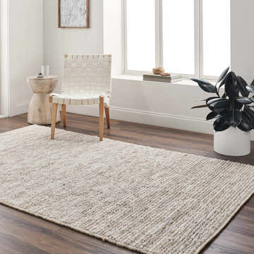 Bright entryway with a Glover Bleached Braided Jute Carpet, woven chair, wood side table, and dark wood floors. Roomscene-Rectangle