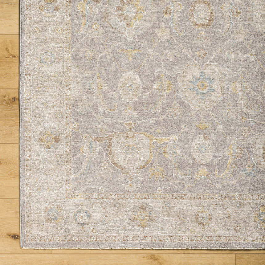 Close-up of Giang Thick Luxe Area Rug in beige and gray with traditional floral pattern on light wood floor. Corner