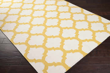 Close-up of the Gilroy Wool Area Rug. Light beige wool rug with a mustard quatrefoil pattern on dark wood floors. Corner