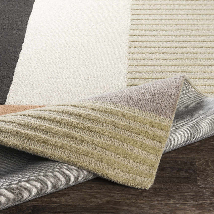 Close up of the geometric Glenmavis Area Rug. Colors include black, beige, gray, peach, and tan. Fold