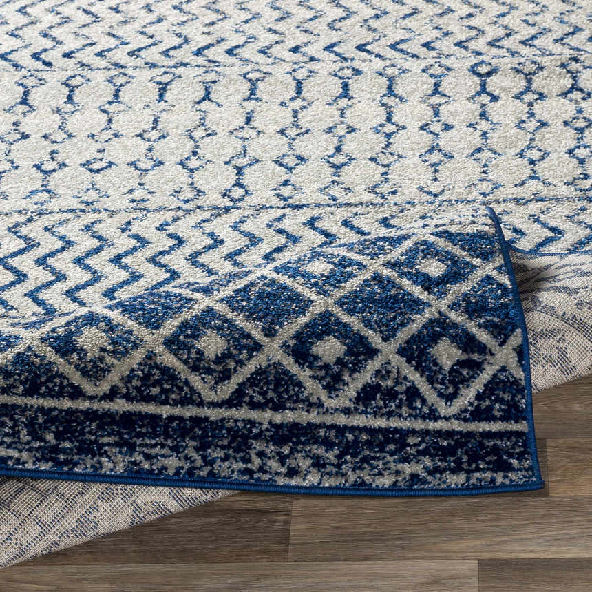 Close up of the Constantin Blue Area Rug showing its geometric blue and white pattern and soft texture. Fold