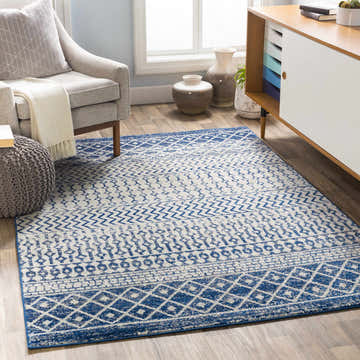 Living room scene with a blue and white Constantin Area Rug, gray chair, and modern cabinet. Roomscene-Rectangle