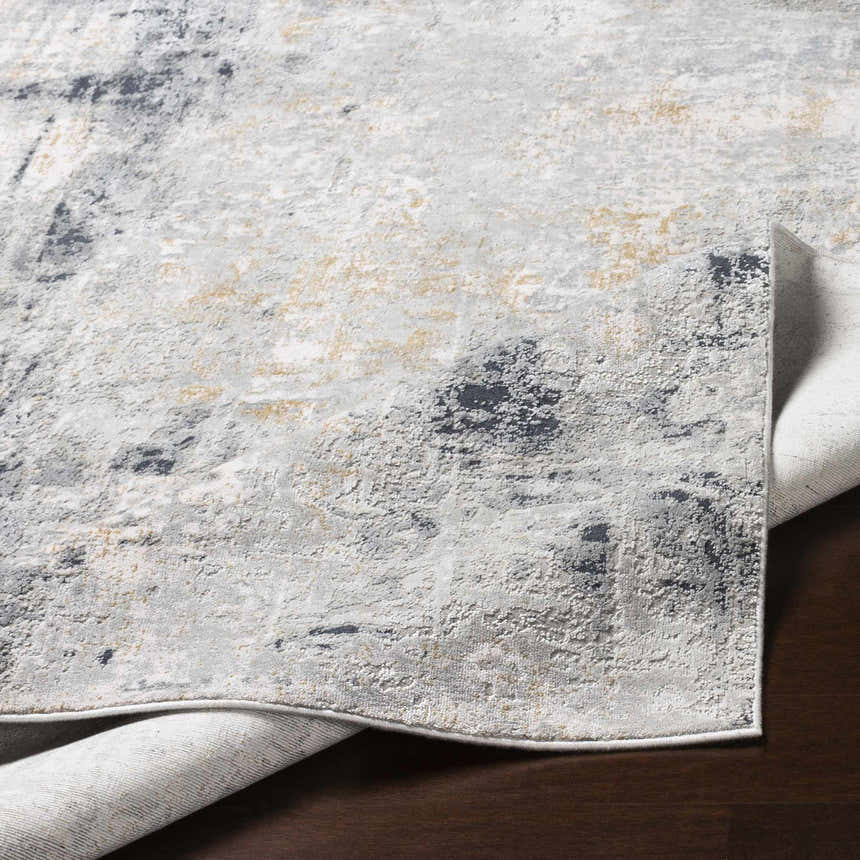 Close-up of the Hayle Area Rug showing its charcoal, gray, light gray, and mustard abstract design and soft texture. Fold