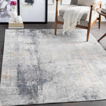 Living room scene with a gray armchair and the contemporary Hayle Area Rug in charcoal, gray, and off-white. Roomscene-Rectangle