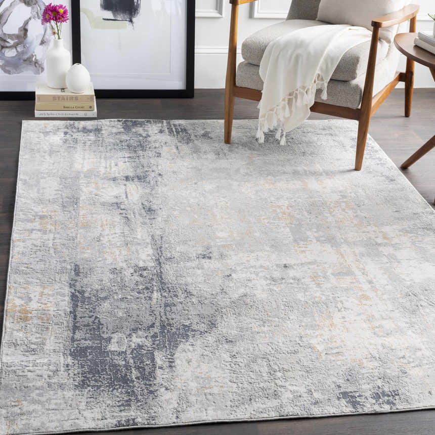 Living room scene with a gray armchair and the contemporary Hayle Area Rug in charcoal, gray, and off-white. Roomscene-Rectangle