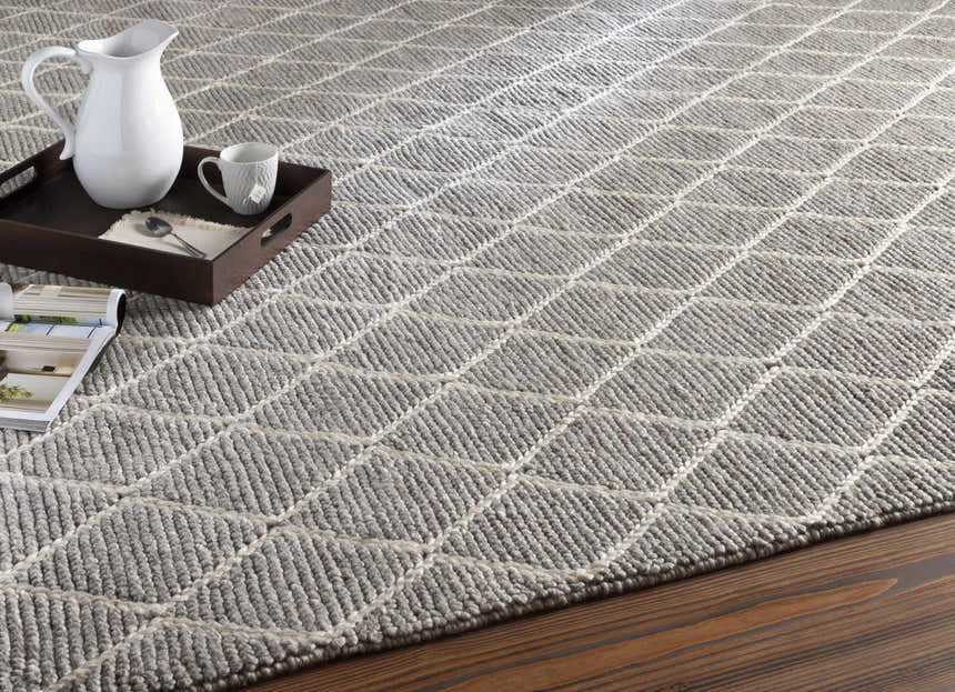Close-up of the Hindley Area Rug, a hand-woven rug in cream and gray with a geometric diamond pattern. Styleshot