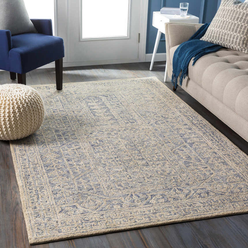 Living room scene with a beige Hinton Wool Area Rug, blue armchair, and beige sofa. Roomscene-Rectangle