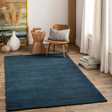 Living room scene with a dark blue Brockton wool rug, wood chair, and neutral decor. Roomscene-Rectangle