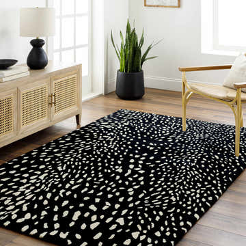 Living room scene with an Athena Black Giraffe Print Wool Rug, wood floors, cane cabinet, gold chair, and snake plant. Roomscene-Rectangle