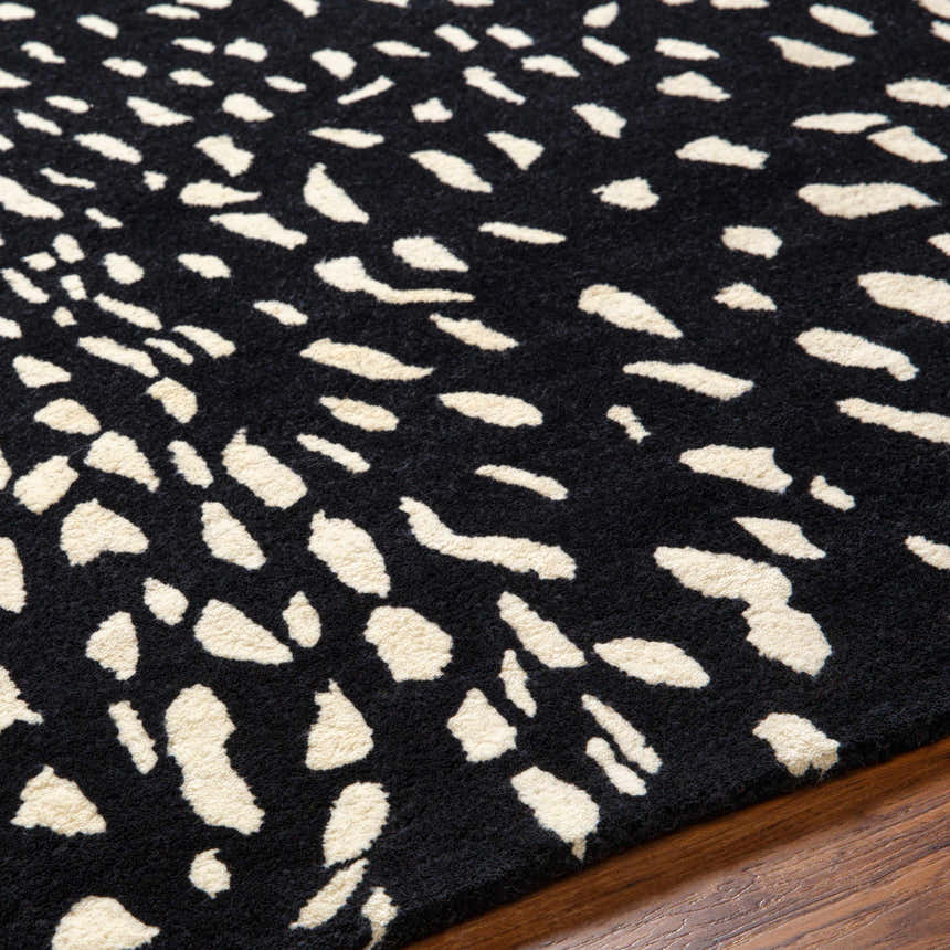 Close-up of the Athena Black Giraffe Print Wool Rug, showcasing its black and beige animal-inspired pattern and hand-tufted texture. Texture