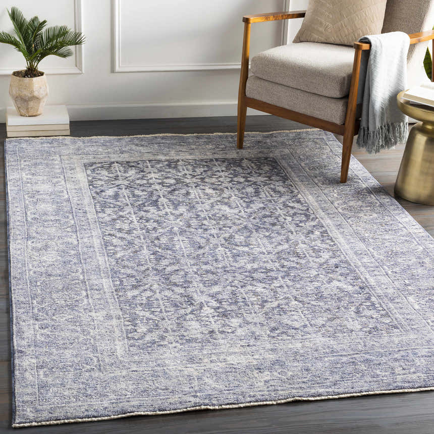 Living room scene with a denim Housatonic Area Rug, beige chair, and gold side table. Roomscene-Rectangle
