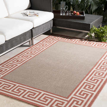 Outdoor patio scene with a Houtz Red Border Greek Rug, white sofa, and black wicker table. Roomscene-Rectangle