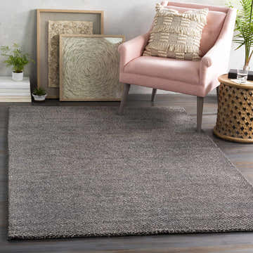 Living room scene with a charcoal Hoyt Carpet, pink chair, and neutral toned artwork. Roomscene-Rectangle