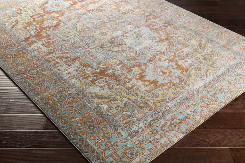 Close-up of a rectangular Hardwick Performance Rug. Bohemian style with brick red, brown, and pale blue oriental pattern. Corner