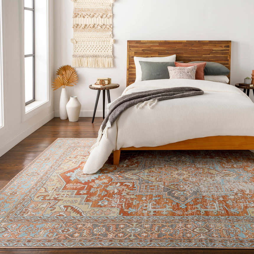 Bedroom scene with a brick red, brown, and blue Hardwick Performance Rug under a wooden bed frame. Roomscene-Rectangle
