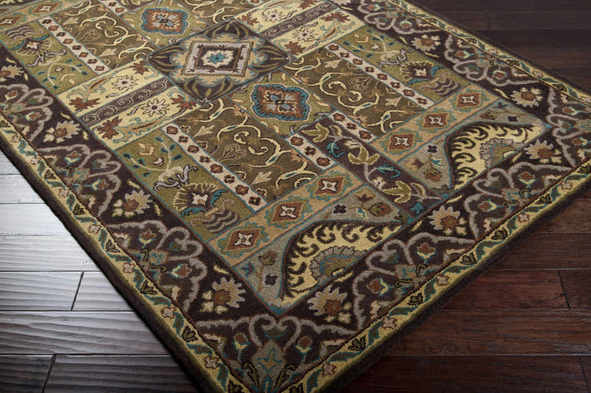 Close-up of the Huguenot rug, a 100% wool, hand-tufted rug with beige, brown, olive, and teal farmhouse-style patterns. Corner